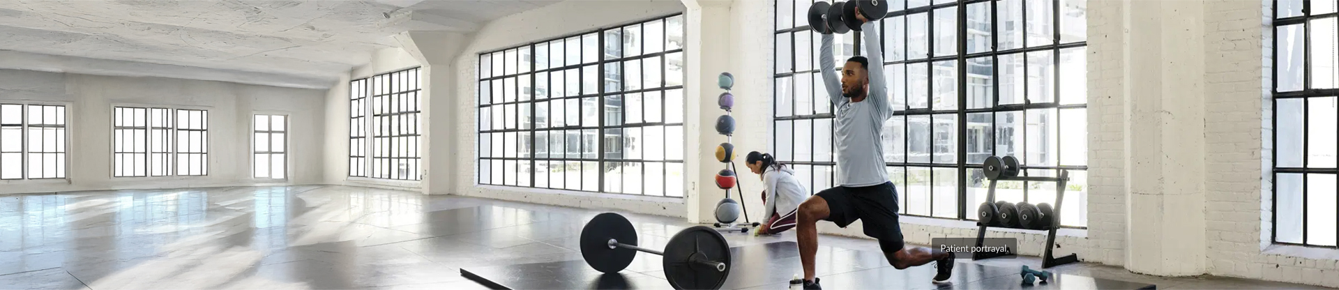 Man in a lunge lifting dumbbells in the gym with a woman in background
