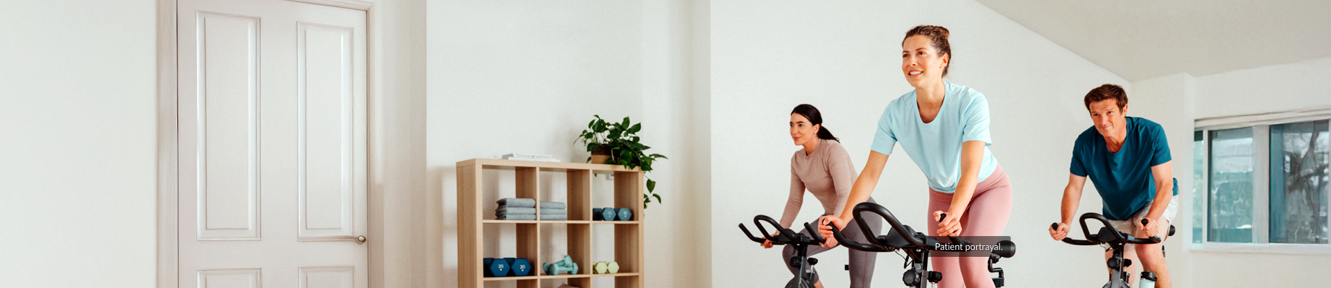 3 people (two women and a man) at the gym doing a spin class on indoor bicycles
