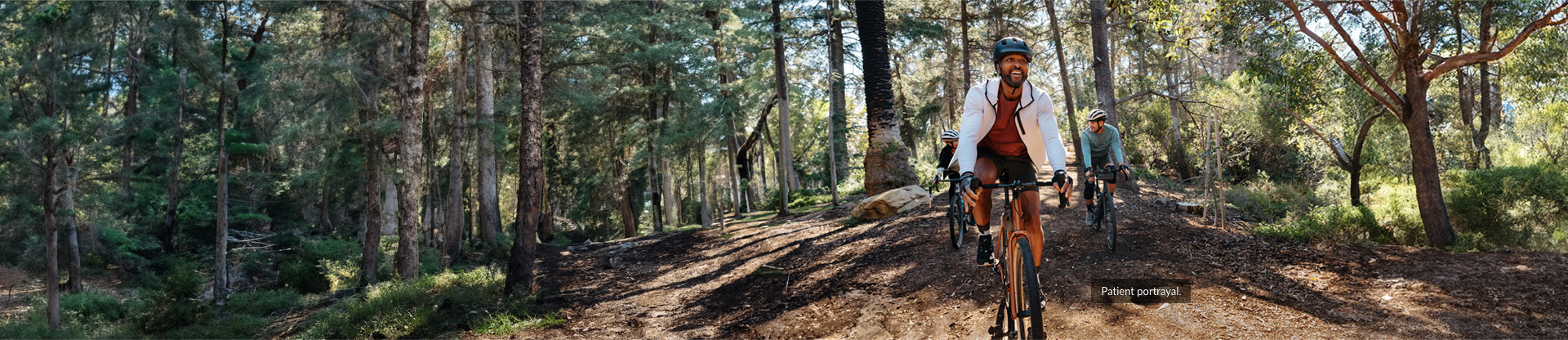 3 men cycling throughout a forest chatting and smiling as friends