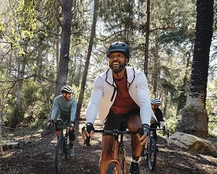 3 men cycling throughout a forest chatting and smiling as friends
