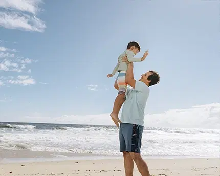 Father lifting up a child above his head in at a beach